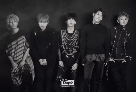 HD PC desktop wallpaper showing a five-member K-pop band in a moody black-and-white group portrait, layered outfits and chains, music-themed background.