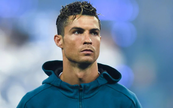 HD desktop wallpaper featuring Cristiano Ronaldo, the renowned Portuguese soccer player, focused and sporting a blue hoodie against a blurred background. Tags: Portuguese, soccer, Cristiano Ronaldo, sports.