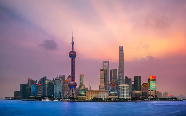 HD wallpaper of Shanghai's skyline featuring the iconic Oriental Pearl Tower and modern skyscrapers against a colorful sunset sky over the city in China.
