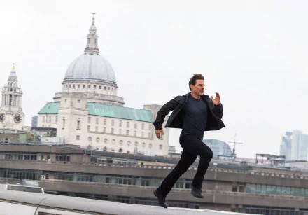 Tom Cruise as Ethan Hunt in a 4K Ultra HD desktop wallpaper from the movie Mission: Impossible – Fallout, captured mid-action with a cityscape backdrop.
