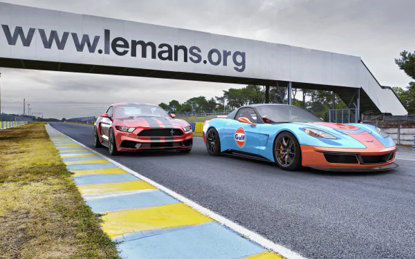 4K Ultra HD desktop wallpaper of a red Ford Mustang GT and blue-orange Chevrolet Corvette (C6) sports cars side-by-side on the Le Mans racetrack.