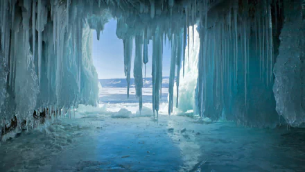 8K Ultra HD winter cave scene showcasing nature’s icy stalactites and frozen floor, framing a bright, cold landscape beyond the ice formations.