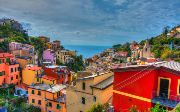 Vibrant, colorful houses of Riomaggiore, Cinque Terre — an HD desktop wallpaper of man-made village terraces cascading to the sea horizon.