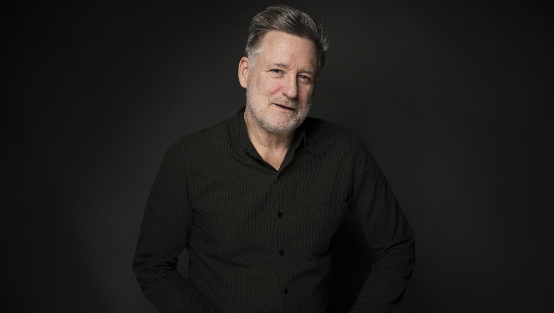 HD desktop wallpaper featuring Bill Pullman in a black shirt, smiling against a dark background.