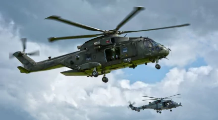 Two military AgustaWestland AW101 helicopters fly against a cloudy sky in this HD desktop wallpaper and background.