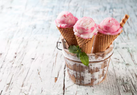 5K Ultra HD PC desktop wallpaper still-life of food: three pink ice cream scoops in waffle cones in a rustic wooden bucket on a whitewashed table, garnished with mint and a wafer stick.