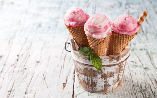5K Ultra HD PC desktop wallpaper still-life of food: three pink ice cream scoops in waffle cones in a rustic wooden bucket on a whitewashed table, garnished with mint and a wafer stick.