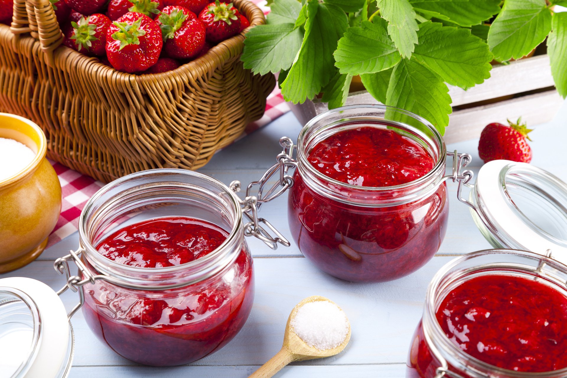 Close-up of fresh strawberries and jars of strawberry jam on a wooden surface, captured in vibrant detail for a 4K Ultra HD desktop wallpaper and background.