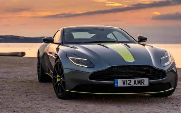Silver Aston Martin DB11 supercar grand tourer parked by a scenic waterfront at sunset, captured in 4K Ultra HD as a PC desktop wallpaper and background.