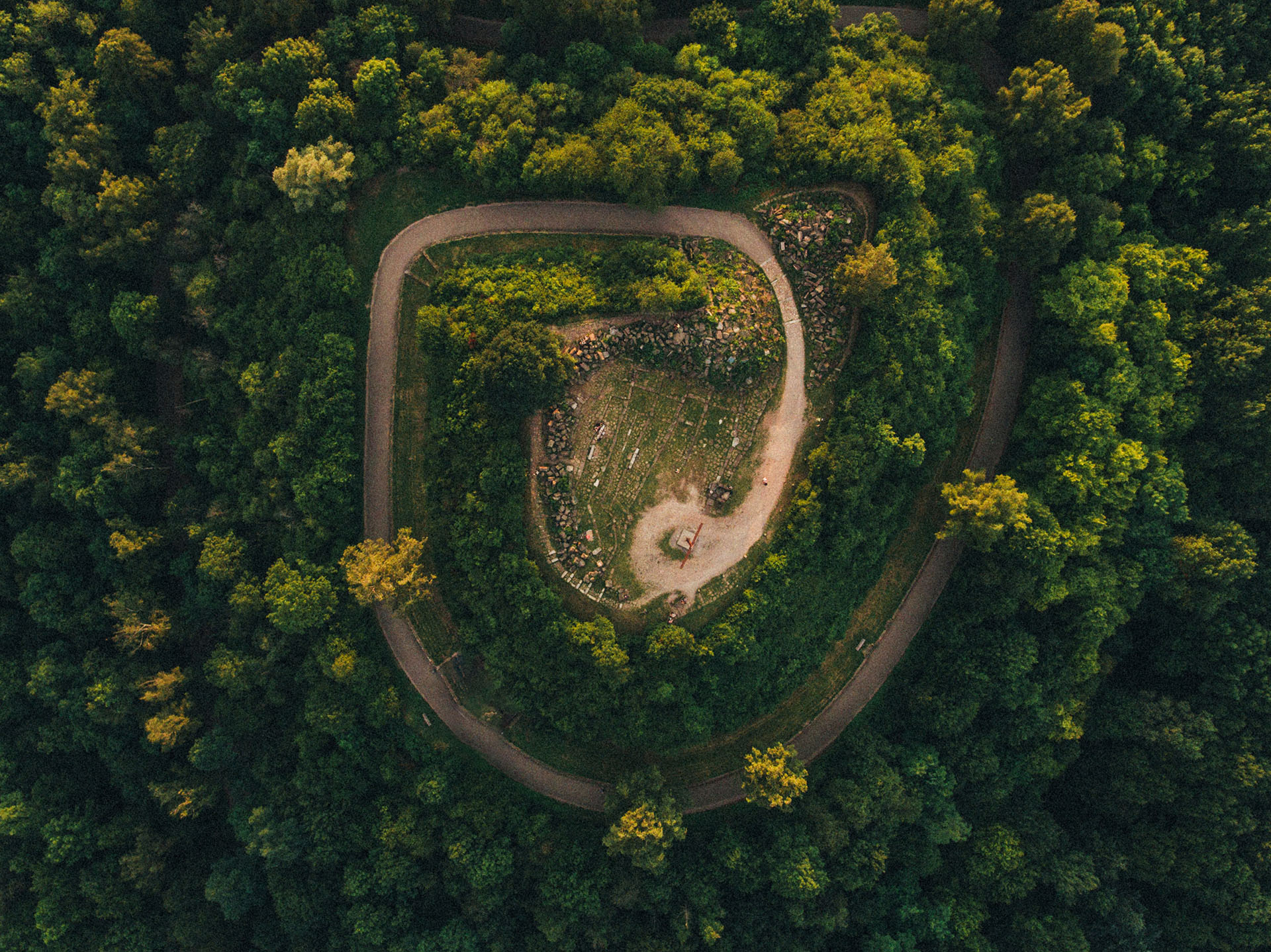 A drone shot of a spiral road in a forest by Max Boettinger