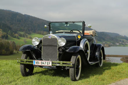 Black vintage Ford Model A convertible classic car parked on grass with hills and a lake in the background, captured in 4K Ultra HD for desktop wallpaper.