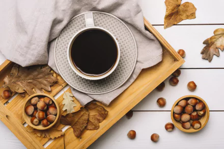 5K Ultra HD PC desktop wallpaper food still life: cup of black coffee on a tray with hazelnuts, bowls of hazelnuts and autumn leaves on white wood background.