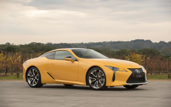 Yellow Lexus LC 500 parked on a road with vineyards and an overcast sky — 2K Quad HD PC desktop wallpaper.