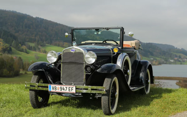 Black vintage Ford Model A convertible classic car parked on grass with hills and a lake in the background, captured in 4K Ultra HD for desktop wallpaper.