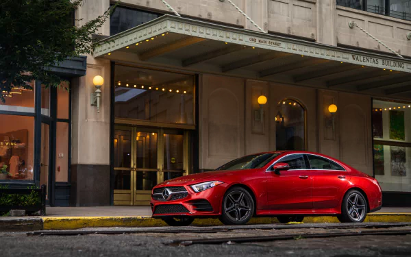 A red Mercedes-Benz CLS-Class sedan parked in front of an elegant building, captured in 4K Ultra HD as a striking car wallpaper and desktop background.