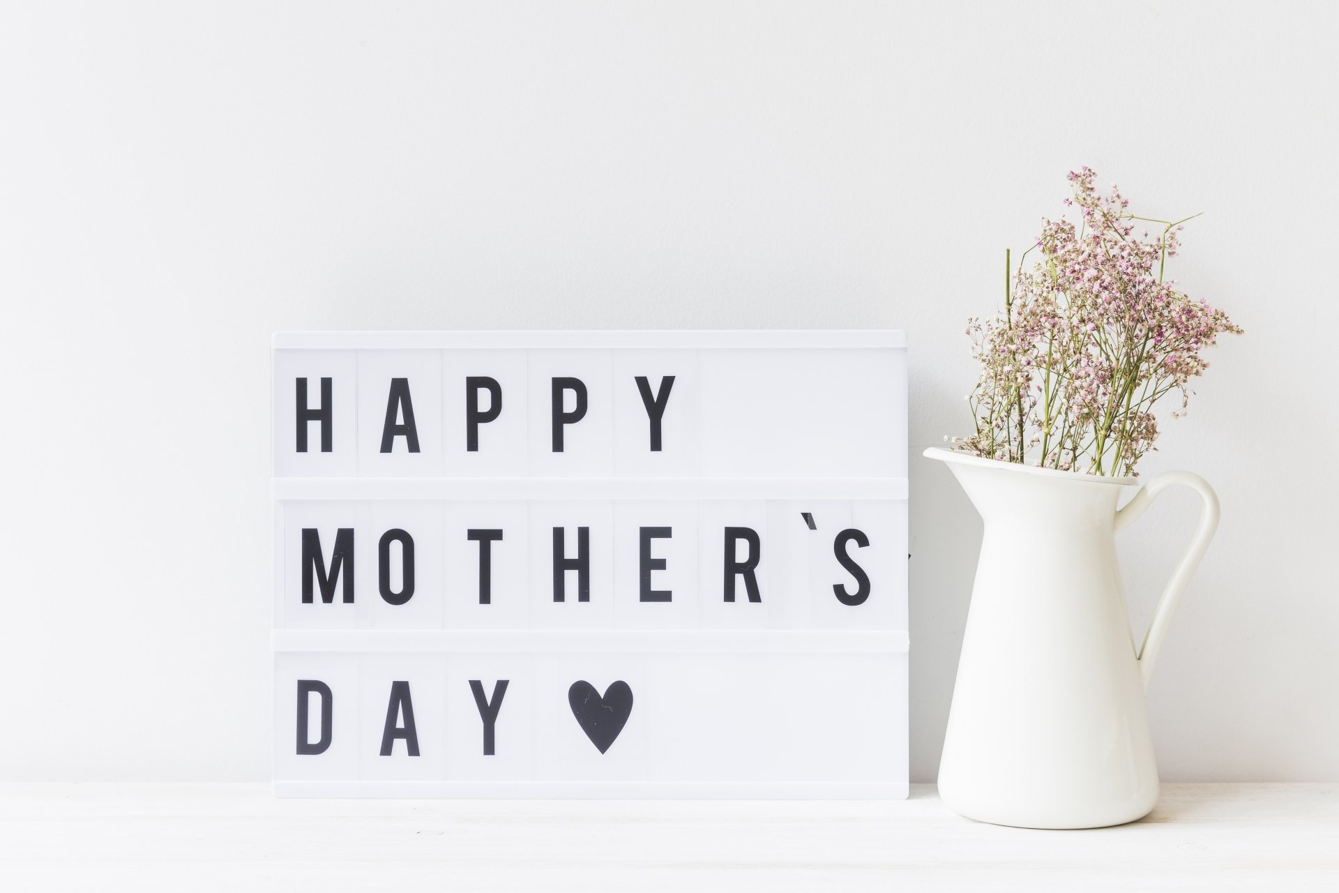 4K Ultra HD Mother's Day desktop wallpaper: minimalist lightbox reading 'HAPPY MOTHER'S DAY ♥' beside a white pitcher with delicate flowers on a clean holiday background.