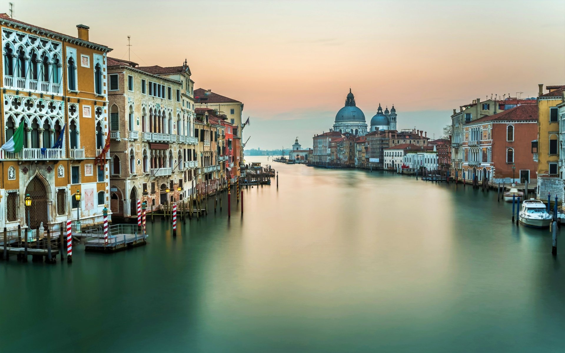 HD desktop wallpaper showcasing Venice’s Grand Canal with historic buildings and calm water under a soft sunset sky, highlighting iconic Italian architecture.