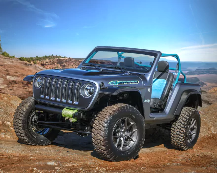 HD desktop wallpaper featuring a rugged Jeep 4-speed vehicle with off-road tires, set against a clear blue sky and rocky desert landscape.