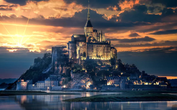 Mont Saint-Michel in France illuminated at sunset, showcasing its iconic religious architecture reflected in calm waters, presented in 4K Ultra HD resolution.
