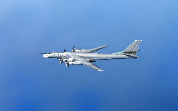 HD desktop wallpaper showing a Tupolev Tu-95 military bomber aircraft flying against a clear blue sky.