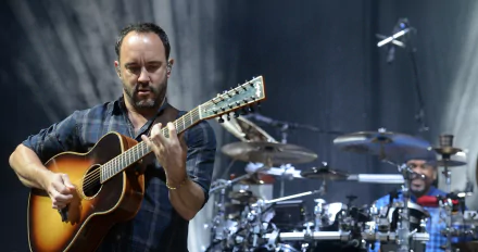 HD wallpaper of Dave Matthews playing guitar with bandmate on drums in the background.