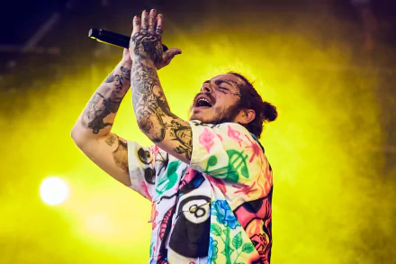 HD desktop wallpaper featuring Post Malone performing on stage with a microphone, showcasing his vibrant tattoos and colorful outfit.