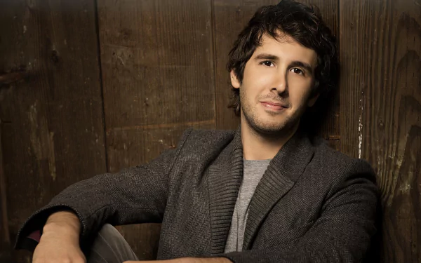 HD desktop wallpaper featuring a person sitting in front of a wooden backdrop, offering a calm and approachable look.