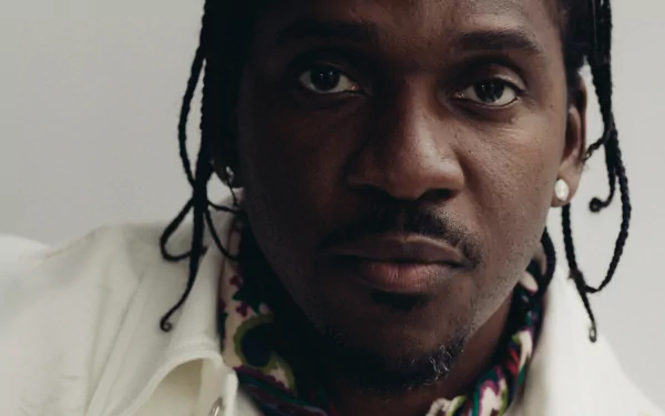 HD desktop wallpaper featuring a close-up portrait of a man with braided hair, looking intently at the camera.