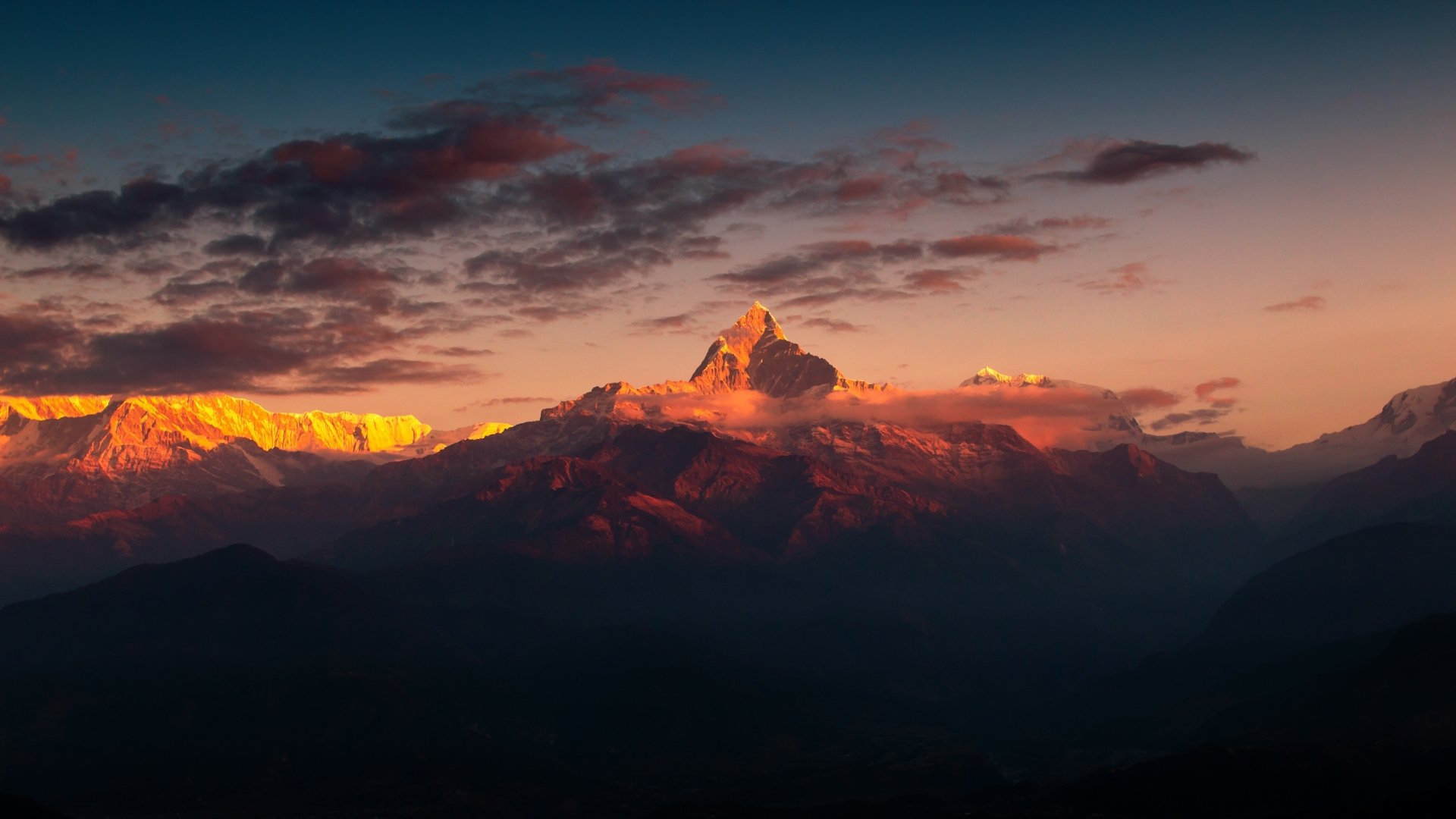 A stunning HD desktop wallpaper showcasing a nature landscape with a majestic mountain bathed in the warm hues of a setting sun.