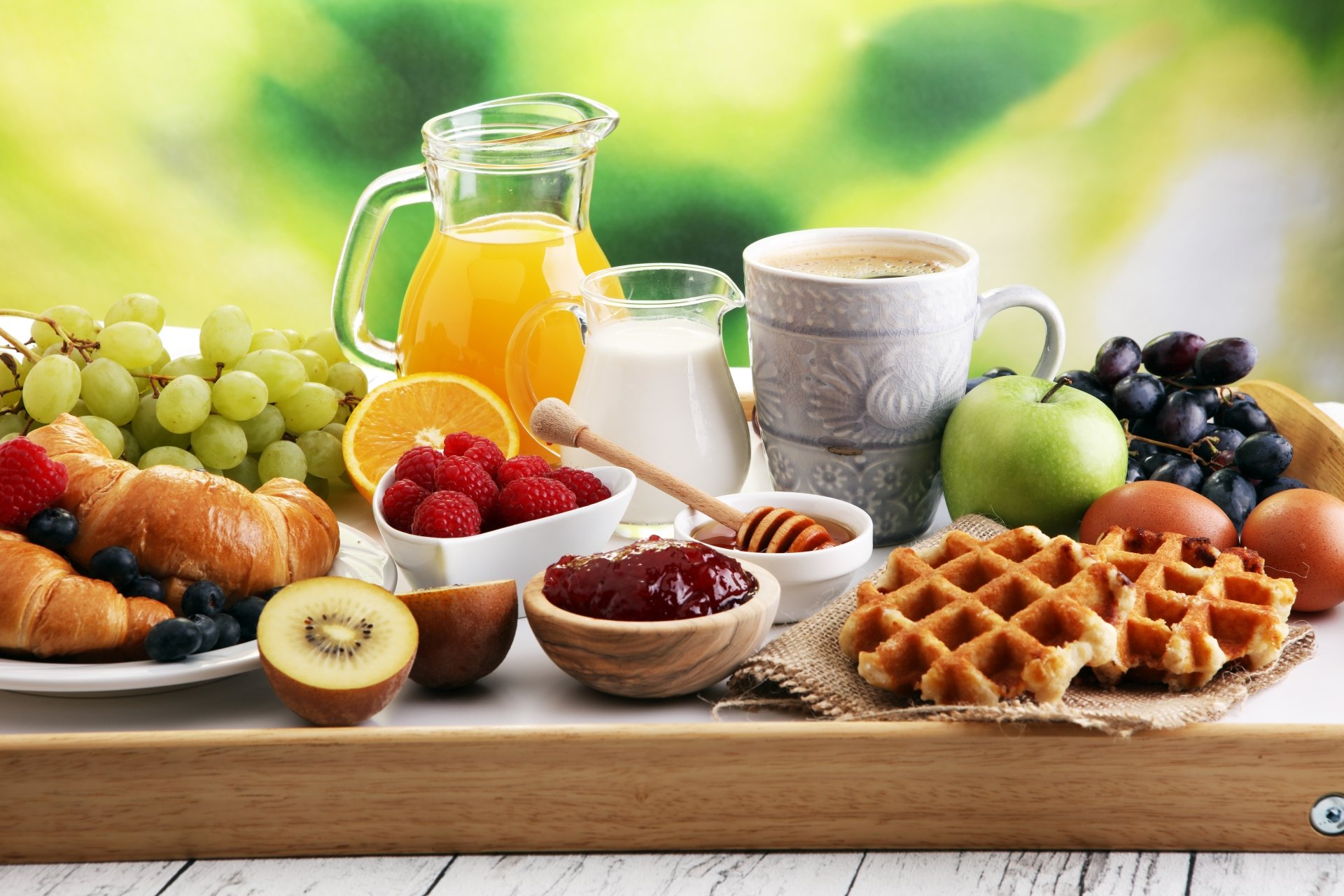 8K Ultra HD PC desktop wallpaper — breakfast still life with croissant, waffle, jam, honey, milk, juice, coffee and fresh fruit on a wooden tray.