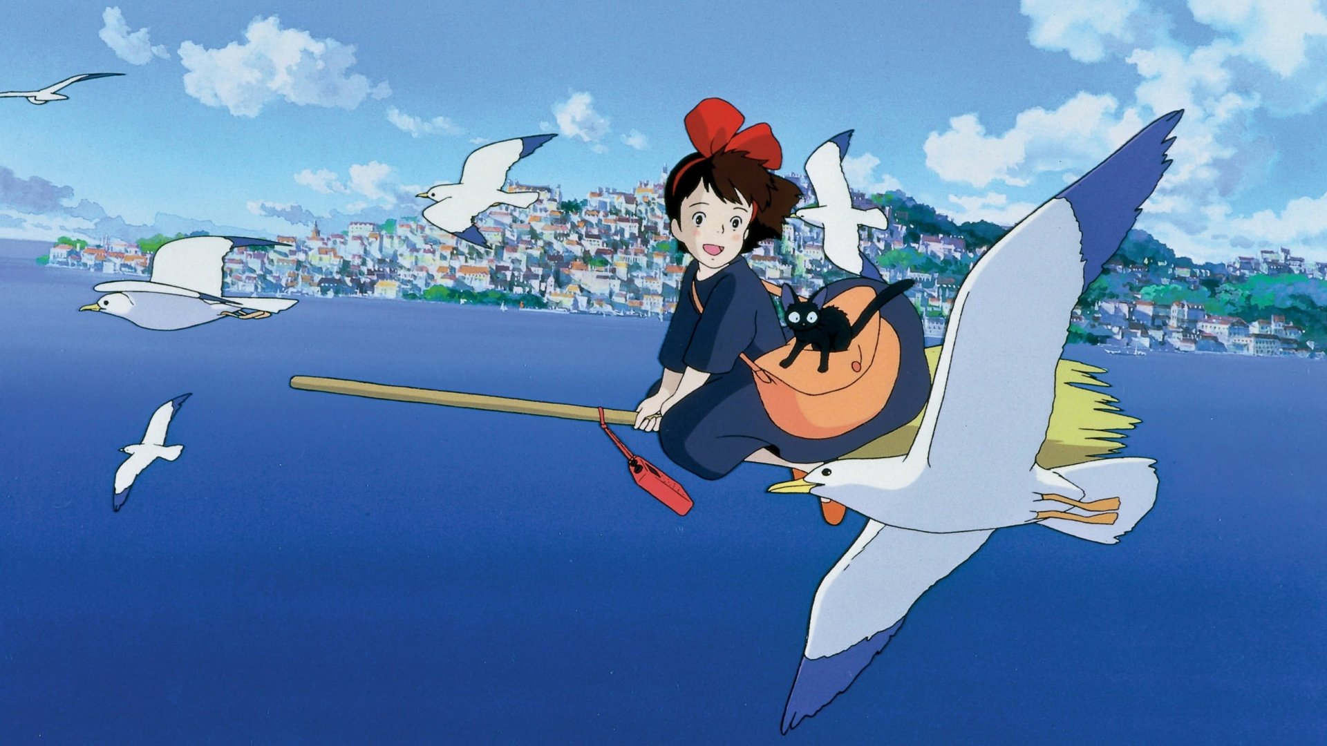 HD desktop wallpaper from the anime Kiki's Delivery Service, featuring Kiki flying on her broomstick with a black cat and seagulls against a scenic backdrop of the ocean and a city.
