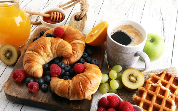 A vibrant 8K Ultra HD still life breakfast scene with croissants, blueberries, raspberries, coffee, juice, kiwi, grapes, apple, orange, honey, and a waffle on a wooden board.
