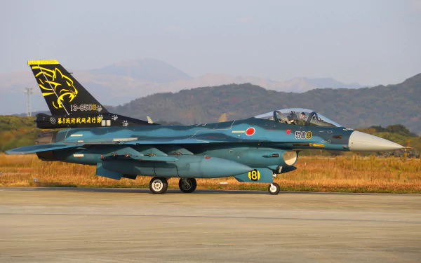 A Mitsubishi F-2 military jet fighter warplane on a runway with mountains in the background, captured in high-detail 4K Ultra HD desktop wallpaper quality.