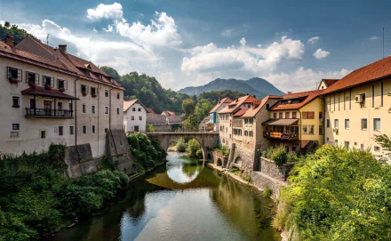 HD PC desktop wallpaper of a picturesque man-made village: colorful riverside houses and a stone bridge reflected in a calm river beneath a bright blue sky.