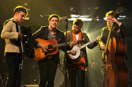 HD wallpaper of Mumford & Sons performing live with instruments under stage lighting.