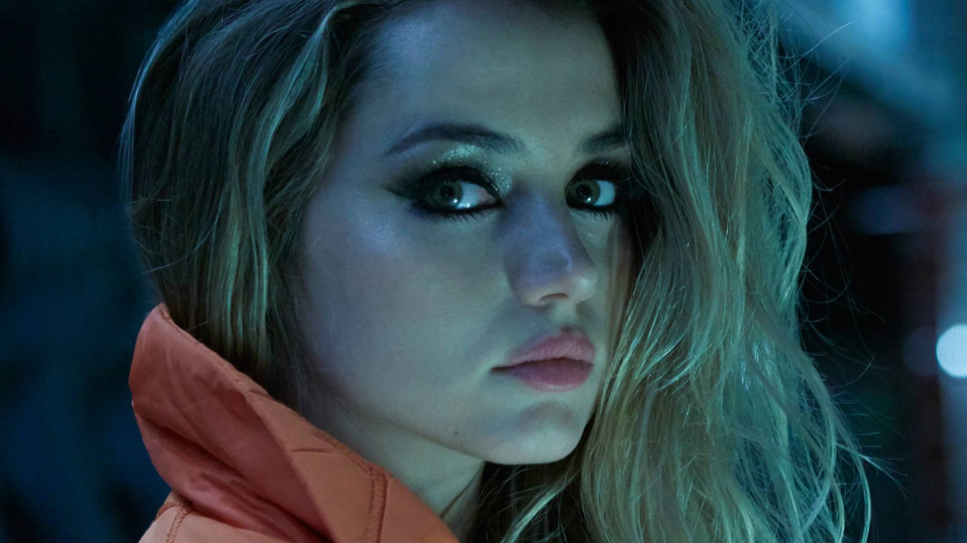HD desktop wallpaper featuring Cuban actress Ana de Armas with blonde hair and striking green eyes in a moody, cinematic close-up portrait.