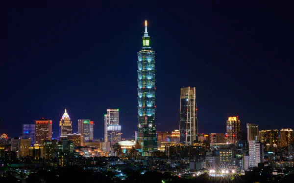 5K Ultra HD desktop wallpaper of Taipei, Taiwan at night: illuminated Taipei 101 skyscraper rising among man-made buildings in the city skyline.