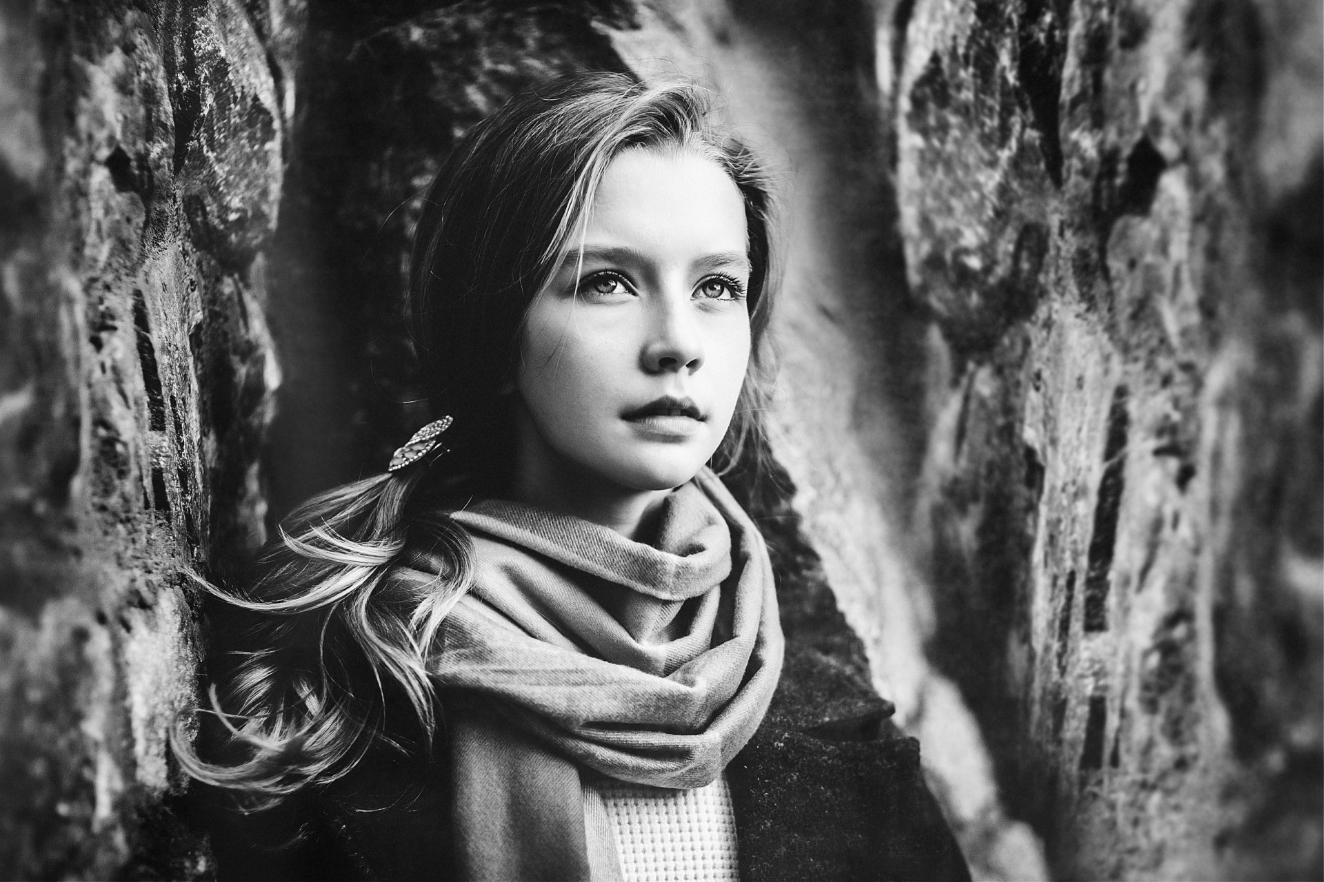 Black-and-white portrait of a woman model wearing a scarf, gazing thoughtfully between rocky walls — 2K Quad HD PC desktop wallpaper/background.