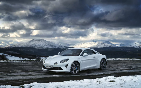 White Alpine A110 sports car parked on a snow-covered road with mountains and dramatic clouds — 2K Quad HD PC desktop wallpaper background.