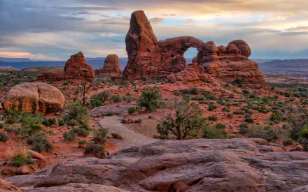 HD PC desktop wallpaper featuring a natural arch formation amidst the desert landscape of Arches National Park under a colorful sky.