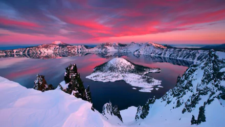 Snow-covered Crater Lake surrounded by snowy mountains under a vibrant pink winter sunset sky, showcasing stunning nature in this HD desktop wallpaper.