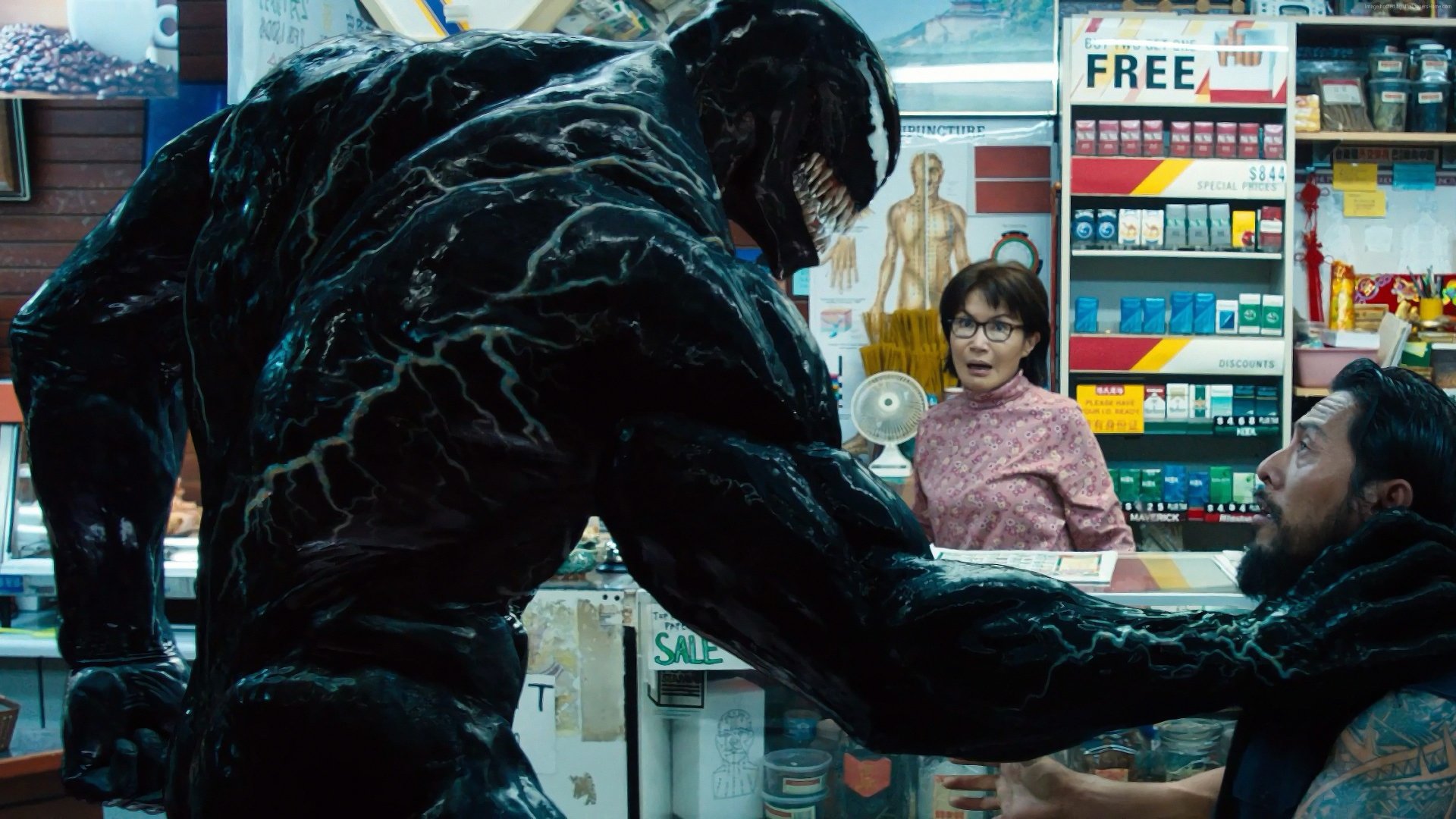 4K Ultra HD PC desktop wallpaper featuring Venom from the movie, depicted menacingly reaching toward a man in a store while a woman looks on.