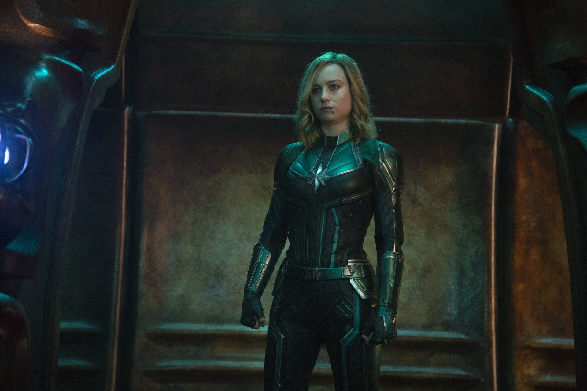 Brie Larson as Captain Marvel in a striking 4K Ultra HD movie scene, featuring her in a dark, armored suit against a metallic backdrop.