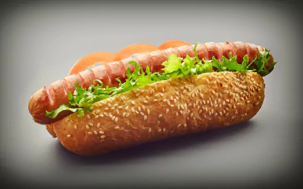 4K Ultra HD wallpaper featuring a vibrant hot dog with sausage, fresh lettuce, and sauce nestled in a sesame seed bun against a neutral background.