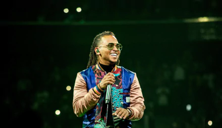 HD desktop wallpaper of a smiling performer on stage, tagged with Ozuna, with a vibrant concert background.